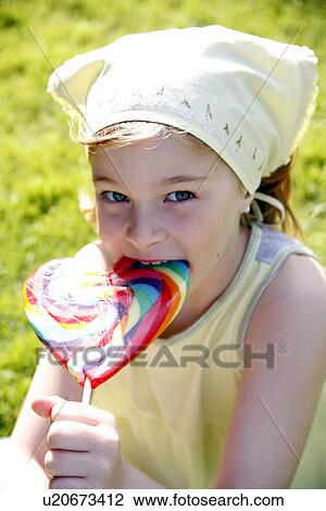 Young girl licking a lollipop View Large Photo Image Stock Image - Young girl licking a lollipop. Fotosearch