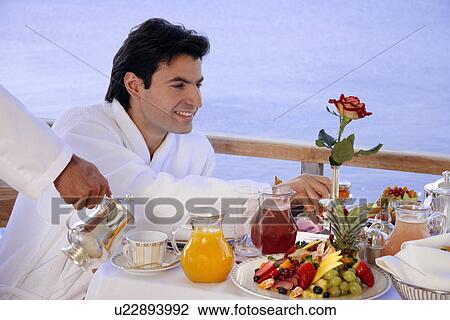 Young man having breakfast on hotel terrace View Large Photo Image Stock Image - Young man having breakfast on hotel terrace. Fotosearch