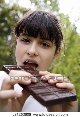 Stock Photo - Young teenage girl eating chocolate. Fotosearch