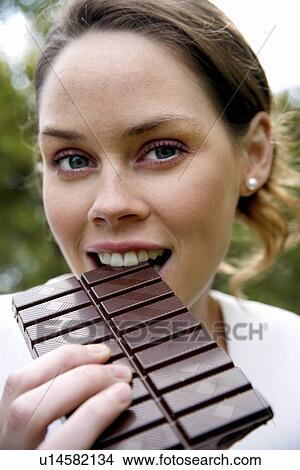 Young woman eating chocolate View Large Photo Image Picture - Young woman eating chocolate. Fotosearch