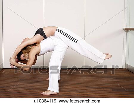 Partners practicing flexibility in yoga and Capoeira programs View Large Photo Image Stock Photo - Partners practicing flexibility in yoga and Capoeira programs. Fotosearch