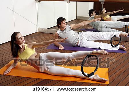 Stock Image - Young man and woman performing a pilates exercise. Fotosearch