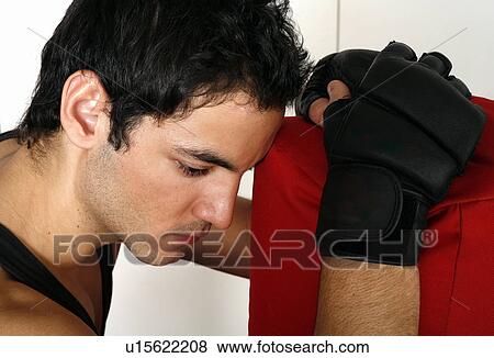 Young man leaning on punching bag View Large Photo Image Stock Photo - Young man leaning on punching bag. Fotosearch