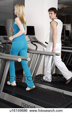 Young woman and man on treadmill View Large Photo Image Stock Photograph - Young woman and man on treadmill. Fotosearch