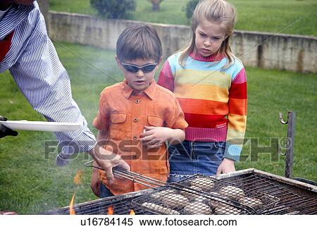 Boy and girl standing near a barbecue View Large Photo Image Stock Photography - Boy and girl standing near a barbecue. Fotosearch
