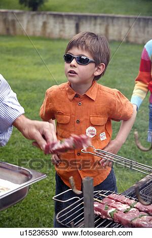Boy standing near a barbecue View Large Photo Image Stock Image - Boy standing near a barbecue. Fotosearch