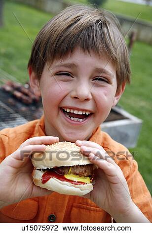 Little boy eating a hamburger View Large Photo Image Stock Image - Little boy eating a hamburger. Fotosearch