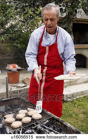Mature man cooking food at a barbecue View Large Photo Image Stock Photography - Mature man cooking food at a barbecue. Fotosearch