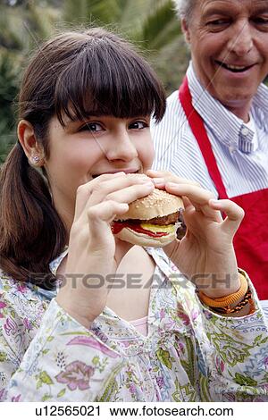 Stock Image - Teenage girl eating a hamburger. Fotosearch