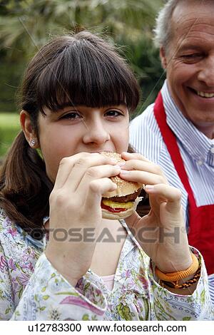 Stock Image - Teenage girl eating a hamburger. Fotosearch