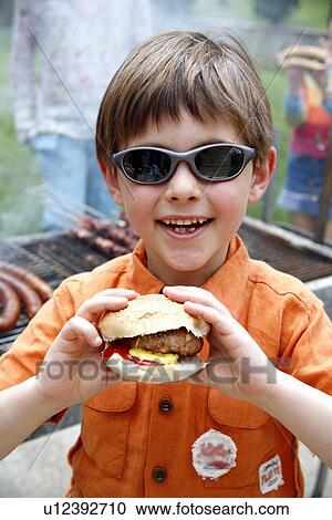 Young boy eating a hamburger View Large Photo Image Stock Image - Young boy eating a hamburger. Fotosearch