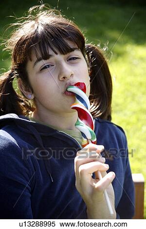 Teenage girl licking a lollipop View Large Photo Image Stock Photography - Teenage girl licking a lollipop. Fotosearch