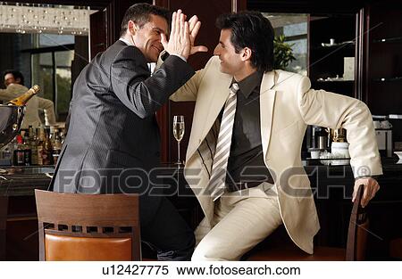 Stock Photography - Two men slapping hands in agreement at a bar. Fotosearch