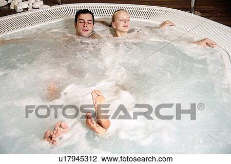 Stock Image - One man with woman in jacuzzi at a spa. Fotosearch