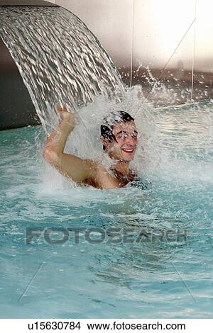 Young man standing under water spray in spa pool View Large Photo Image Picture - Young man standing under water spray in spa pool. Fotosearch