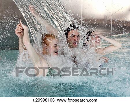 Young people standing under water spray in spa pool View Large Photo Image Stock Image - Young people standing under water spray in spa pool. Fotosearch