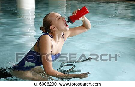 Stock Image - Young woman on exercise bike in spa pool. Fotosearch