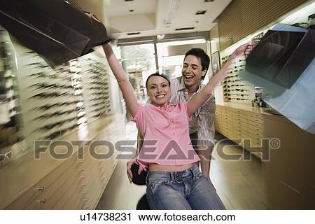 Happy couple posing with shopping bags in a sunglasses store View Large Photo Image Stock Image - Happy couple posing with shopping bags in a sunglasses store. Fotosearch
