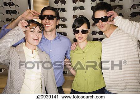 Stock Image - Two couples posing with sunglasses in store. Fotosearch