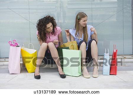 Stock Photo - Two women sitting with shopping bags. Fotosearch