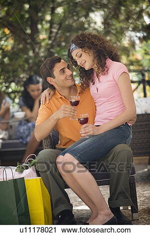 Woman sitting on man's lap with shopping bags in cafe View Large Photo Image Stock Image - Woman sitting on man's lap with shopping bags in cafe. Fotosearch