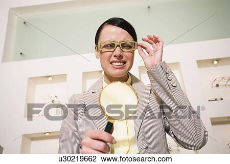 Stock Image - Woman with magnifying glass in store. Fotosearch