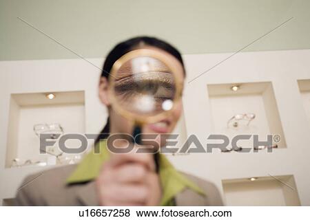 Stock Photo - Woman with magnifying glass on eye. Fotosearch