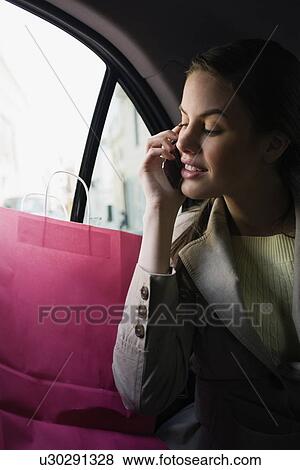 Woman with shopping bags and cell phone in a taxi View Large Photo Image Stock Photo - Woman with shopping bags and cell phone in a taxi. Fotosearch