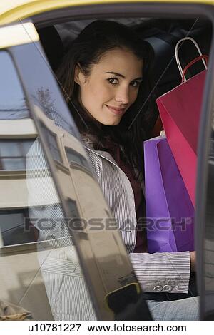 Stock Photo - Woman with shopping bags in a taxi. Fotosearch