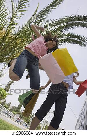 Picture - Women with shopping bags jumping. Fotosearch