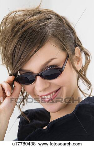 Stock Photo - Portrait of young woman wearing sunglasses. Fotosearch