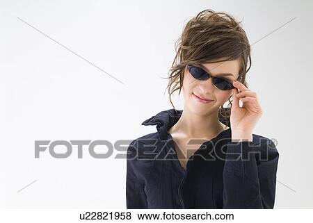 Stock Photo - Portrait of young woman wearing sunglasses. Fotosearch