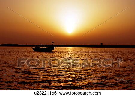 Stock Photograph - silhouette, dubai, creek, deira, boat, sunrise, sunset. Fotosearch