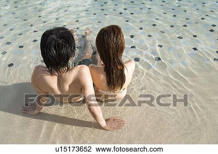 Stock Image - Couple in a swimming pool, Saipan, Rear View. Fotosearch