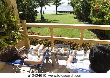Stock Image - Young couple relaxing at balcony, Saipan. Fotosearch