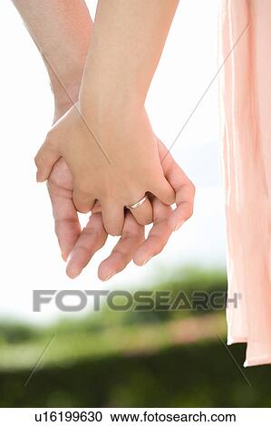Stock Image - Young couple standing hand in hand, differential focus, Saipan, USA . Fotosearch