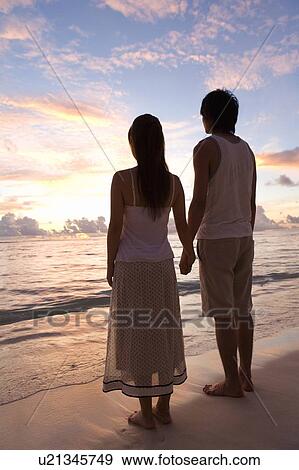 Young couple standing on beach, hand in hand, Saipan, USA View Large Photo Image Stock Photo - Young couple standing on beach, hand in hand, Saipan, USA . Fotosearch