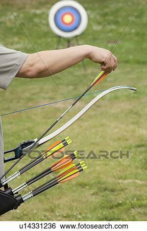 Archer taking arrow from holder (focus on foreground) View Large Photo Image Stock Photograph - Archer taking arrow from holder (focus on foreground). Fotosearch