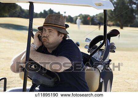 Stock Image - Bored man talking on phone in golf cart. Fotosearch