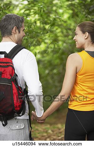 Picture - Couple holding hands in forest, rear view. Fotosearch