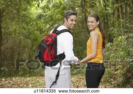 Stock Photography - Couple holding hands in forest, rear view, portrait. Fotosearch