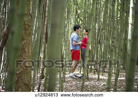 Stock Image - Couple in sports clothing holding hands in forest. Fotosearch