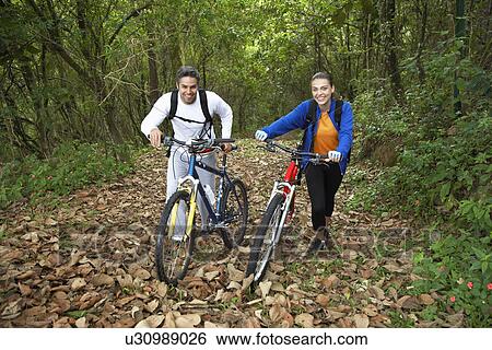 Stock Photograph - Couple with mountain bikes in forest. Fotosearch