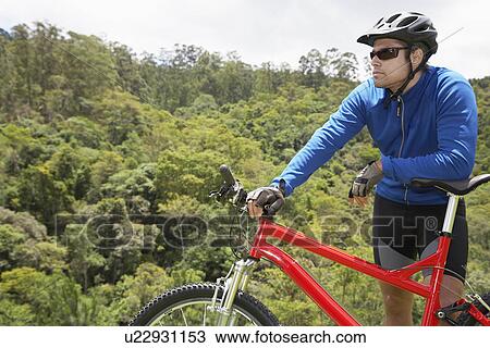 Male cyclist leaning on mountain bike View Large Photo Image Stock Image - Male cyclist leaning on mountain bike. Fotosearch