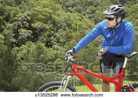 Male cyclist leaning on mountain bike View Large Photo Image Stock Photograph - Male cyclist leaning on mountain bike. Fotosearch