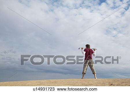 Man with golf club standing on rock View Large Photo Image Stock Image - Man with golf club standing on rock. Fotosearch