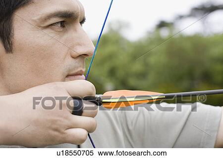Stock Photography - Mid adult man arrow shooting (close-up). Fotosearch