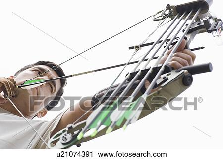 Stock Image - Mid adult man arrow shooting (low angle view). Fotosearch