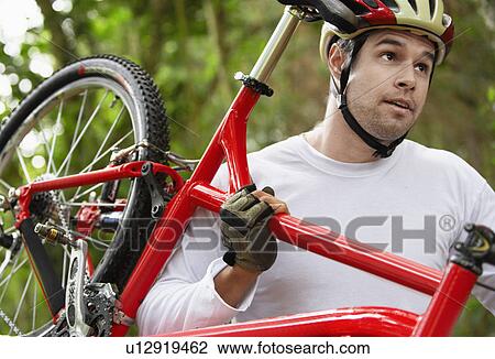 Mid adult man carrying bicycle View Large Photo Image Stock Image - Mid adult man carrying bicycle. Fotosearch
