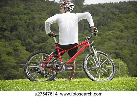 Mid adult man leaning on mountain bike, rear view View Large Photo Image Picture - Mid adult man leaning on mountain bike, rear view. Fotosearch